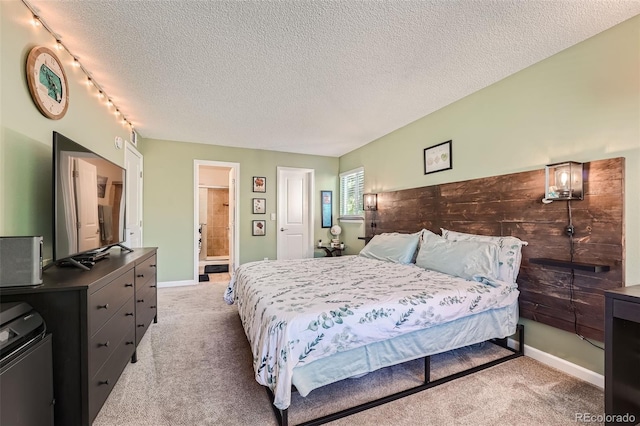 bedroom with connected bathroom, light carpet, and a textured ceiling