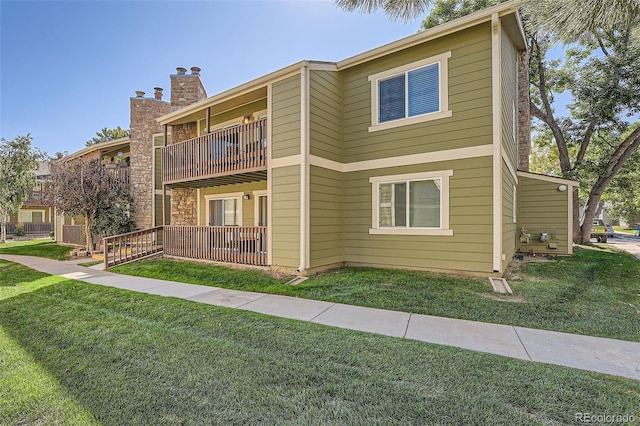 view of front of house featuring a balcony and a front lawn