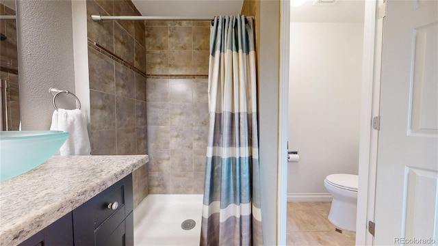 bathroom featuring toilet, vanity, baseboards, tile patterned floors, and a stall shower