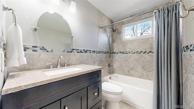 full bath featuring a textured wall, vanity, toilet, and shower / bathtub combination with curtain