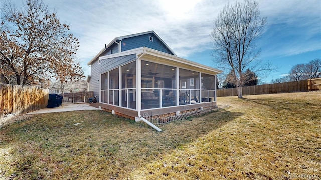 back of property with a yard, a patio, a fenced backyard, and a sunroom