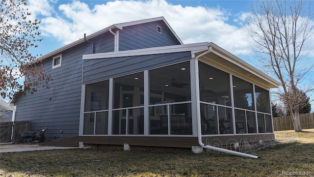 view of side of home with a sunroom, fence, and a lawn