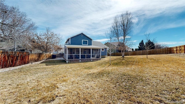 back of property with a sunroom, a fenced backyard, and a lawn