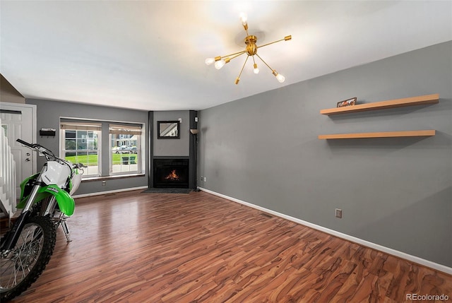 living area with wood finished floors, a chandelier, baseboards, and a fireplace with flush hearth
