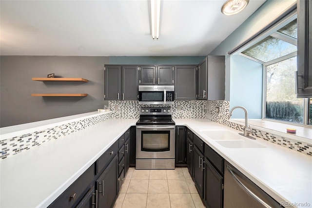 kitchen with stainless steel appliances, a sink, backsplash, and light countertops