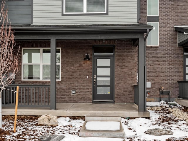 snow covered property entrance featuring a porch