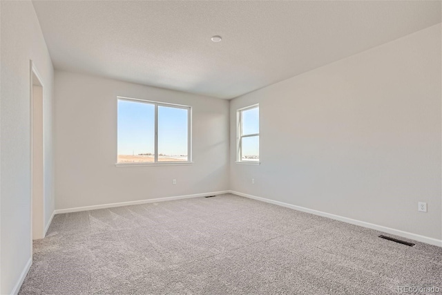 carpeted spare room with a textured ceiling