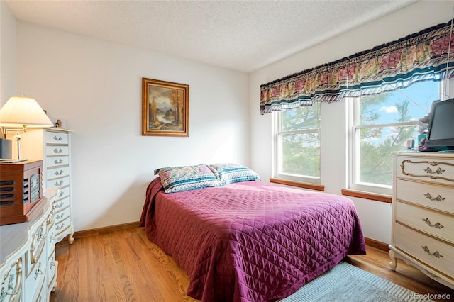 bedroom with a textured ceiling and light hardwood / wood-style flooring