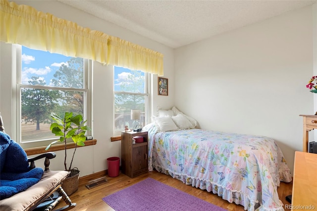 bedroom featuring wood-type flooring, a textured ceiling, and multiple windows