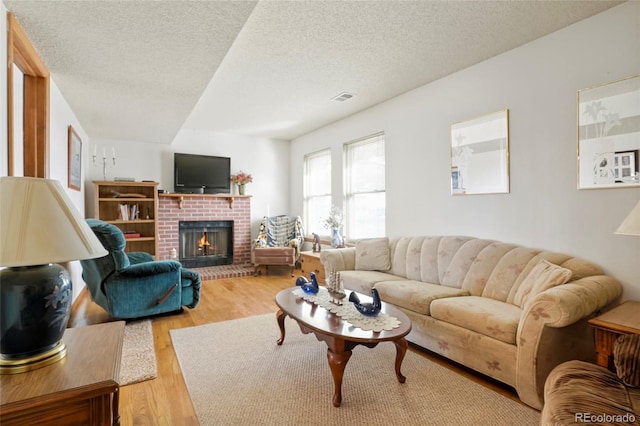 living room with a textured ceiling, a fireplace, and light hardwood / wood-style flooring