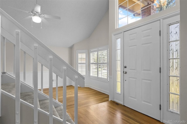 entrance foyer with ceiling fan, hardwood / wood-style floors, vaulted ceiling, and a textured ceiling