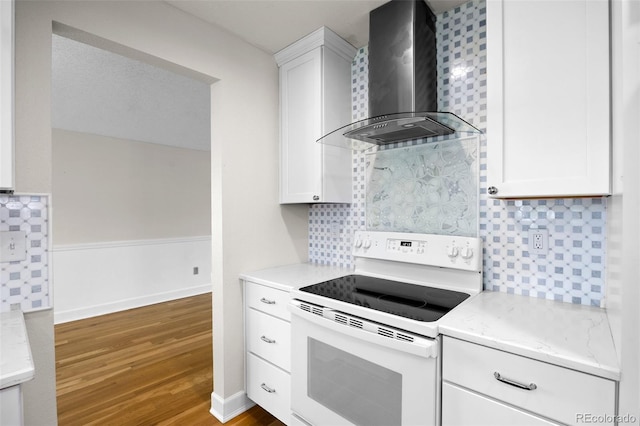 kitchen with white cabinets, wall chimney range hood, white electric stove, and light stone countertops