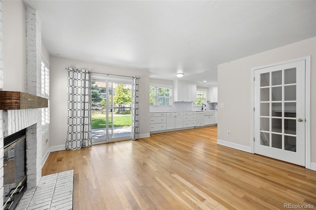 unfurnished living room with sink, light wood-type flooring, and a fireplace