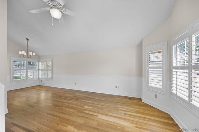 unfurnished room with light hardwood / wood-style floors, vaulted ceiling, and ceiling fan with notable chandelier