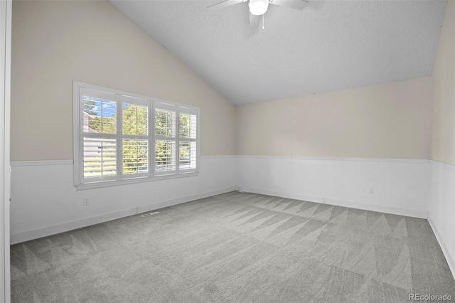 empty room featuring lofted ceiling, a textured ceiling, ceiling fan, and light carpet