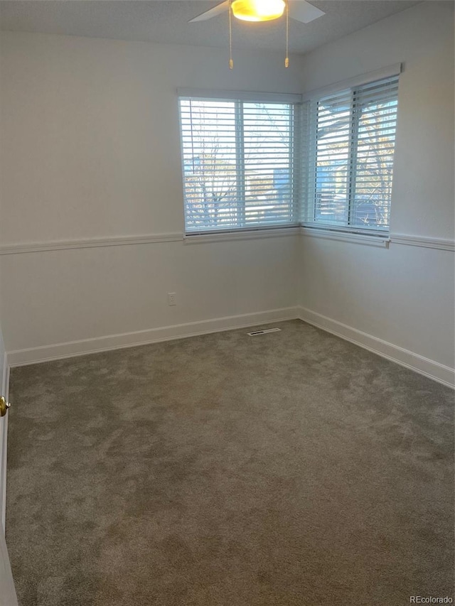 spare room featuring ceiling fan and dark carpet