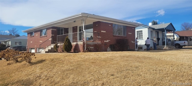 view of front of property with brick siding, an attached garage, a porch, and a front lawn