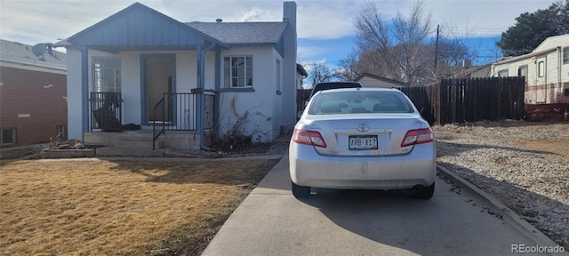 view of front of home featuring stucco siding, roof with shingles, a front lawn, and fence