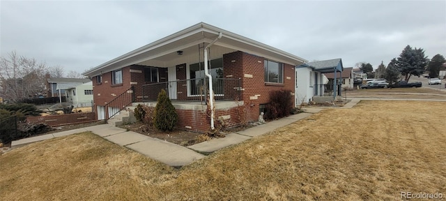 view of front facade with a porch, brick siding, and a front yard