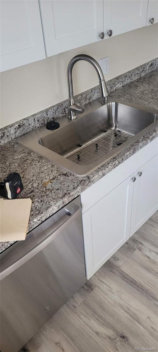 8001 Lowell Blvd, Westminster, CO 80031 - details featuring a sink, light wood-style flooring, white cabinetry, and stainless steel dishwasher