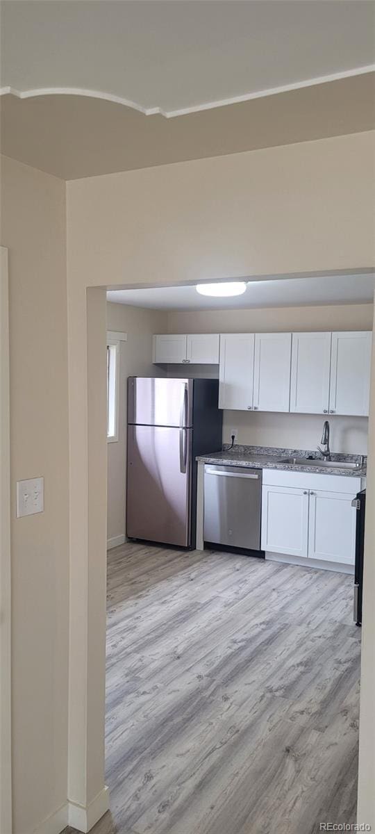 8001 Lowell Blvd, Westminster, CO 80031 - kitchen featuring baseboards, a sink, white cabinets, appliances with stainless steel finishes, and light wood-type flooring