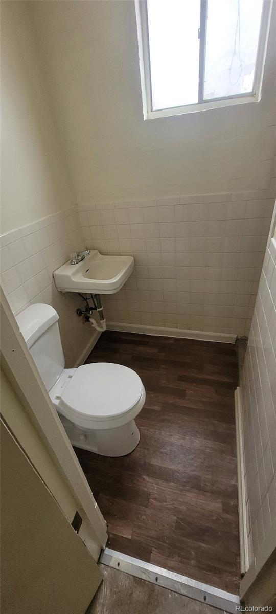 8001 Lowell Blvd, Westminster, CO 80031 - half bathroom featuring toilet, wood finished floors, a wealth of natural light, and wainscoting