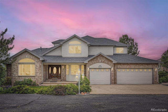 6335 Oberon Rd, Arvada, CO 80004 - view of front of property featuring stucco siding, driveway, brick siding, a shingled roof, and covered porch