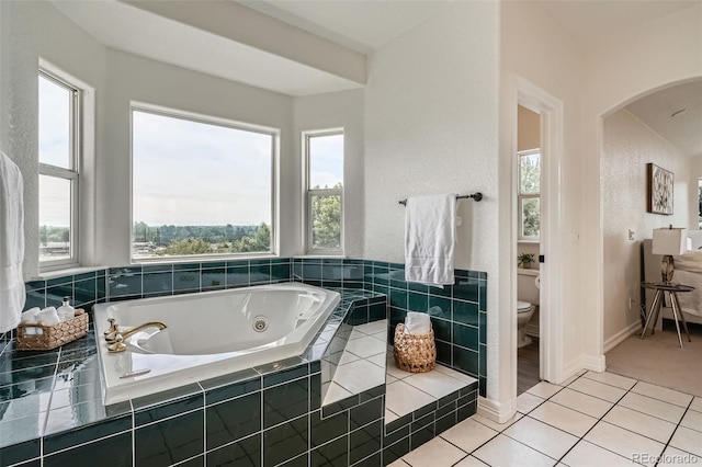 6335 Oberon Rd, Arvada, CO 80004 - bathroom featuring toilet, a jetted tub, healthy amount of natural light, and tile patterned floors