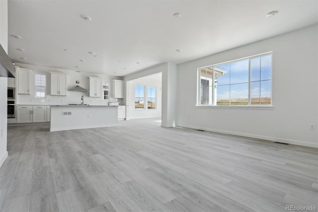 25234 E Warren Pl, Aurora, CO 80018 - unfurnished living room with a sink, plenty of natural light, light wood finished floors, and baseboards