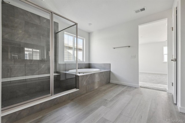 25234 E Warren Pl, Aurora, CO 80018 - bathroom featuring wood finished floors, a garden tub, a stall shower, and baseboards