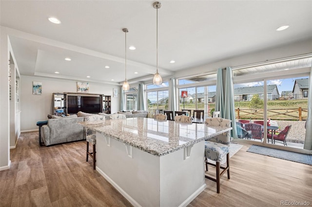 kitchen featuring baseboards, light wood finished floors, light stone counters, and a breakfast bar