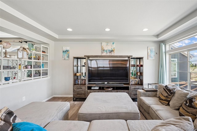 living area with baseboards, recessed lighting, a tray ceiling, and wood finished floors