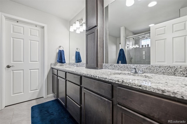 full bath with double vanity, a shower stall, a sink, and tile patterned flooring