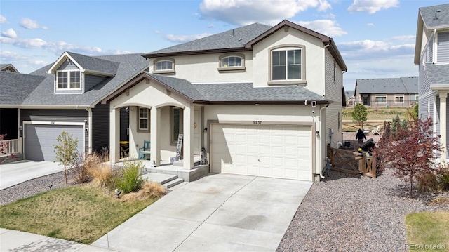 traditional-style house with covered porch, driveway, roof with shingles, an attached garage, and stucco siding