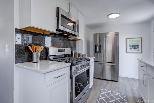 kitchen with backsplash, stainless steel appliances, light hardwood / wood-style floors, and white cabinetry