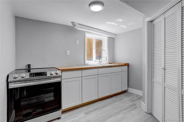 kitchen featuring white cabinets, stainless steel electric stove, light hardwood / wood-style floors, and sink