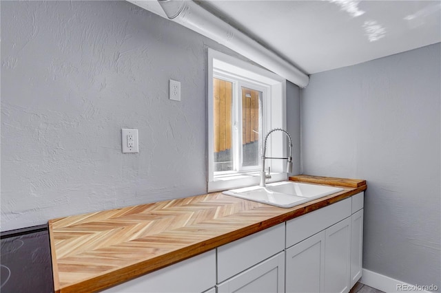 interior space featuring white cabinets, butcher block counters, and sink