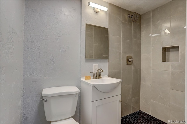 bathroom with vanity, toilet, and a tile shower