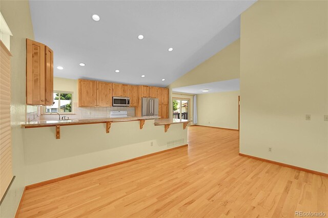 1624 Daphne St, Broomfield, CO 80020 - kitchen featuring appliances with stainless steel finishes, a breakfast bar area, light wood-style flooring, a peninsula, and light countertops