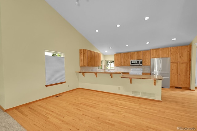 1624 Daphne St, Broomfield, CO 80020 - kitchen with stainless steel appliances, a kitchen breakfast bar, a peninsula, high vaulted ceiling, and light wood-style floors