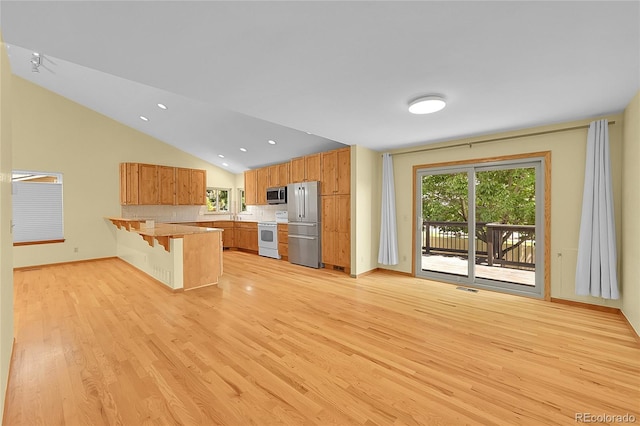1624 Daphne St, Broomfield, CO 80020 - kitchen with stainless steel appliances, a peninsula, light wood-type flooring, a breakfast bar, and vaulted ceiling