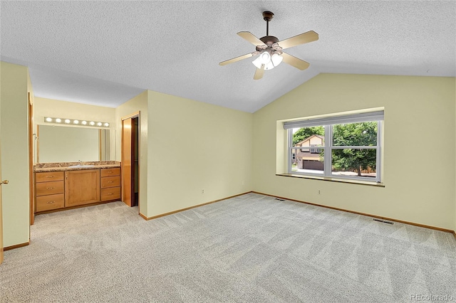 1624 Daphne St, Broomfield, CO 80020 - unfurnished bedroom with light colored carpet, vaulted ceiling, a textured ceiling, a ceiling fan, and connected bathroom