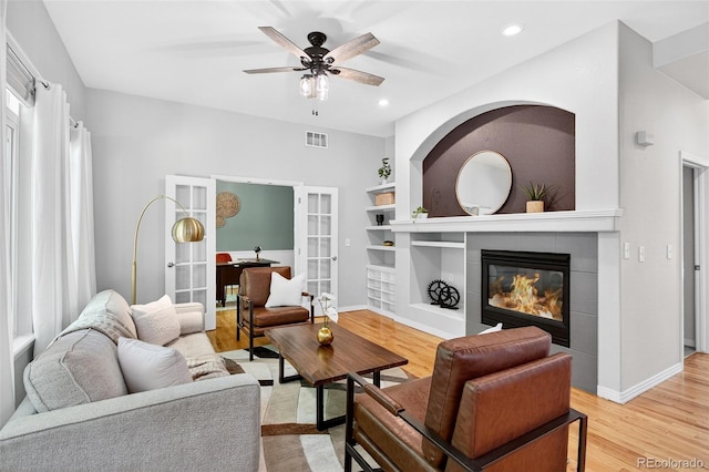 4501 Whitehall Ln, Highlands Ranch, CO 80126 - living room featuring french doors, a ceiling fan, a fireplace, light wood-style flooring, and built in shelves
