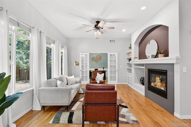 4501 Whitehall Ln, Highlands Ranch, CO 80126 - living area with light wood-style floors, a large fireplace, ceiling fan, and french doors
