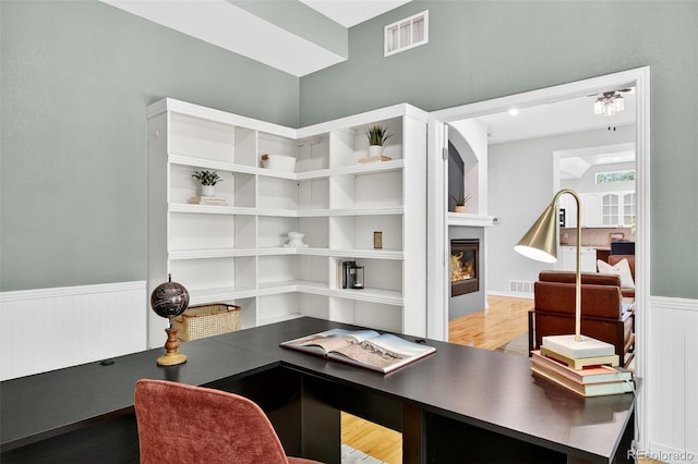 4501 Whitehall Ln, Highlands Ranch, CO 80126 - home office with wainscoting, wood finished floors, and a glass covered fireplace