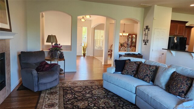 living room with baseboards, a notable chandelier, dark wood finished floors, and a tiled fireplace