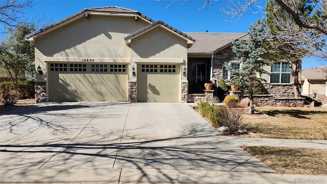 view of front of house with a tile roof, stucco siding, a garage, stone siding, and driveway