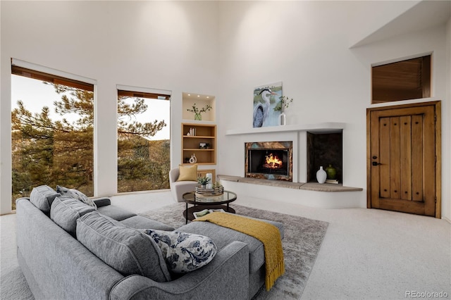 carpeted living room with a towering ceiling and a fireplace