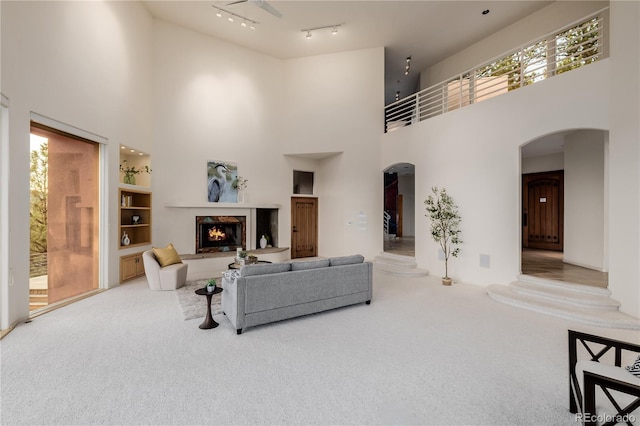 living room with rail lighting, a towering ceiling, and carpet floors