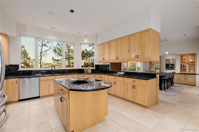 kitchen with stainless steel dishwasher, a kitchen island, hanging light fixtures, and light brown cabinets